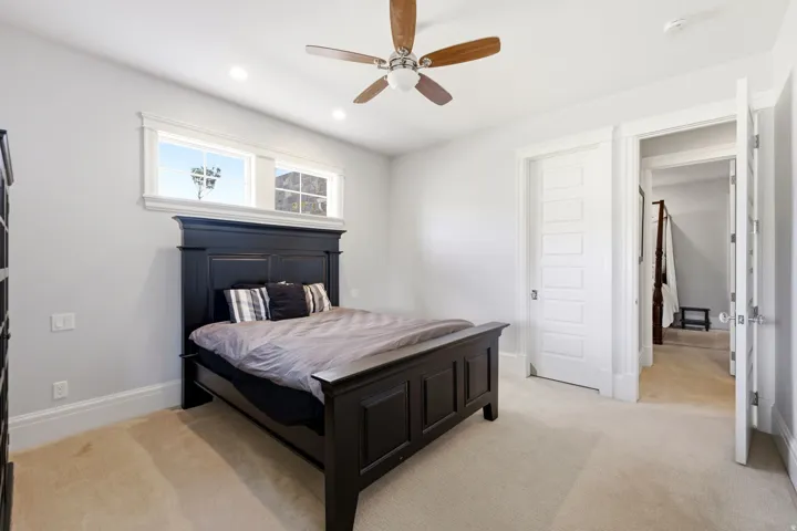 Recessed lighting illuminates neutral-toned carpeting, complemented by a ceiling fan with wood-finish blades