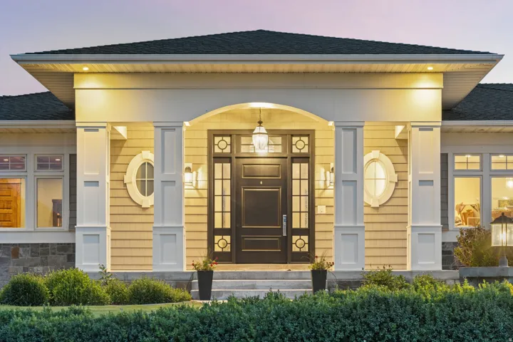 Arched entryway featuring a dark paneled door with glass inserts, flanked by decorative oval windows and sconce lighting