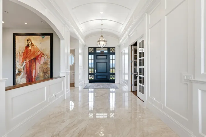 Grand entry hall featuring polished stone flooring and extensive white paneled wall detailing