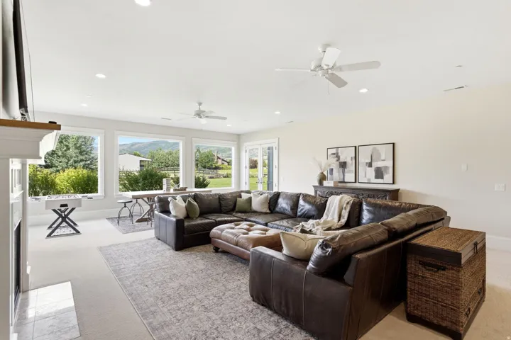 Spacious living area featuring expansive windows, recessed lighting, and ceiling fans