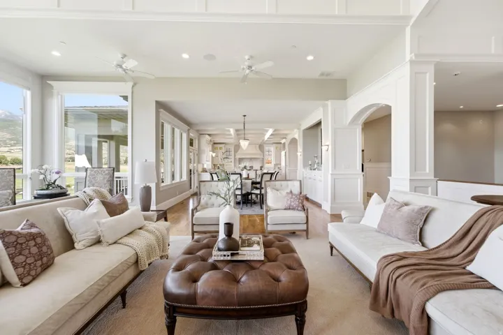 Spacious living area featuring large windows, tray ceilings with recessed lighting, and wood-finish flooring