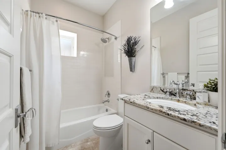 Bathroom featuring a white subway tile shower surround, a white porcelain bathtub, and a window with frosted glass
