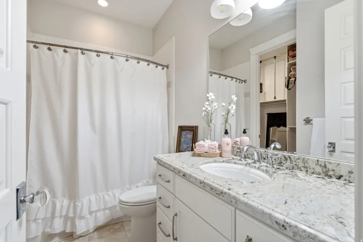 Bathroom featuring a white vanity with silver hardware, a speckled light-toned countertop, and a built-in sink with a chrome faucet