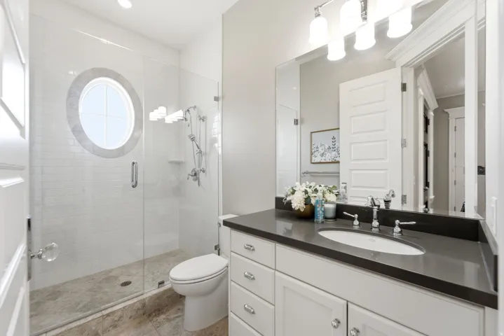 Contemporary bathroom featuring a frameless glass shower enclosure with a unique circular window and white subway tile surround