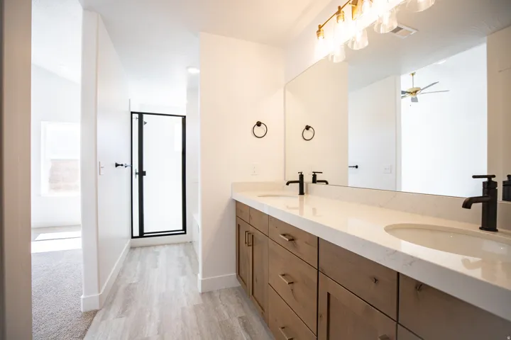 Primary bathroom with a double vanity, upgraded cabinets, and a separate tub and shower