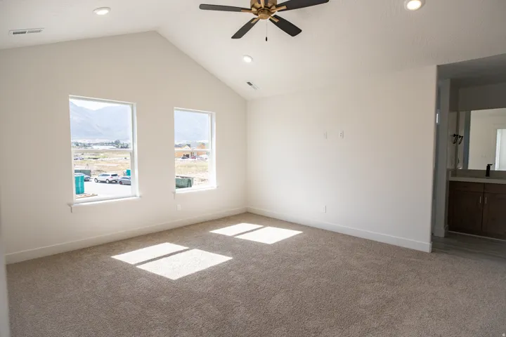 Primary bedroom with vaulted ceilings, recessed lighting, and a ceiling fan