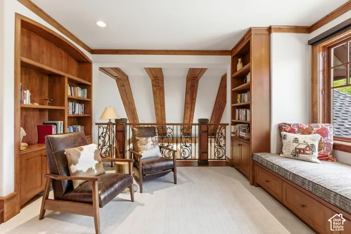 Built-in shelving, wood-framed window, window seat with storage, decorative railing, and exposed wood beams