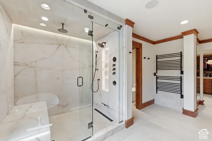 Spacious shower enclosure with glass panels, full-height stone-finish walls, and multiple shower heads