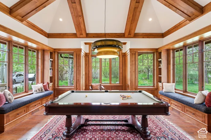 Wood-paneled room with abundant natural light, vaulted ceiling with exposed wood beams, and built-in window seating with integrated storage