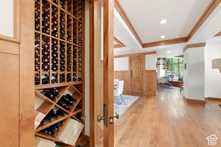 Built-in wine storage, wood-finish flooring, wood wall paneling, and recessed ceiling lighting