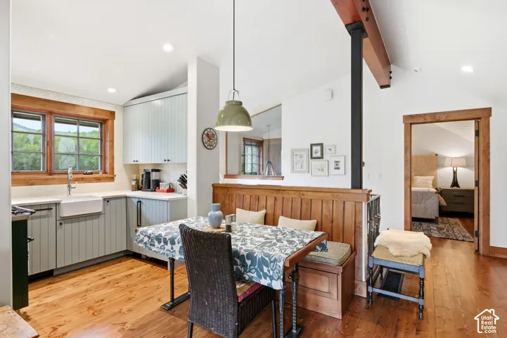 Hardwood flooring throughout, kitchen featuring light-toned cabinetry, farmhouse sink, and light countertops