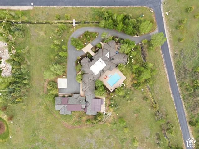 Expansive property with a curved driveway, established landscaping, and an integrated swimming pool