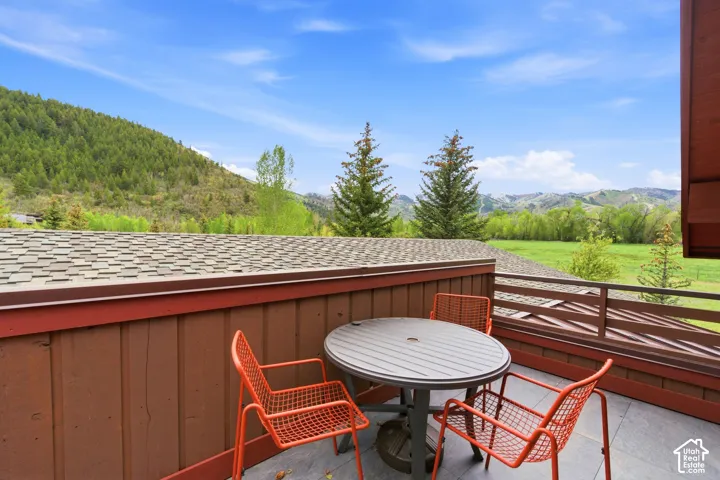 Outdoor deck with dark tile flooring, wood-paneled siding, and a slatted railing