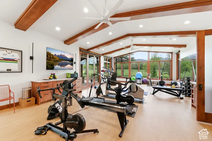 Vaulted ceilings with exposed wood beams, recessed lighting, expansive windows, wood-finish flooring, and built-in cabinetry with a light-toned countertop