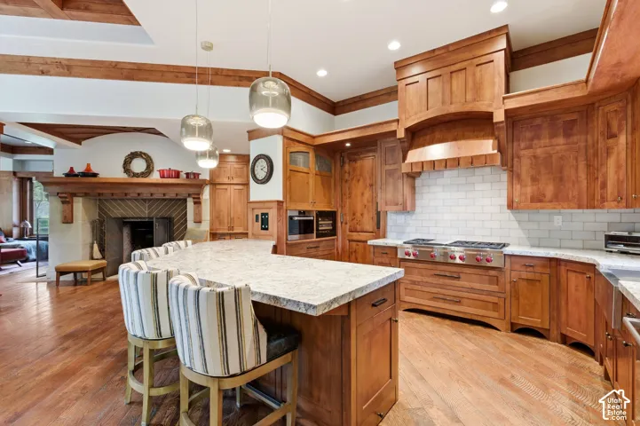 Spacious kitchen with a curved island, wood-finish flooring, custom wood cabinetry, and a professional-grade range