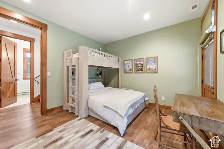 Wood-finish flooring throughout, light green wall finishes, and recessed ceiling lighting