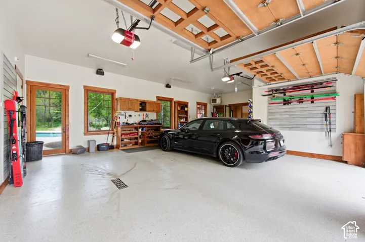 Spacious garage featuring wood-framed windows and doors, built-in cabinetry, and a light-colored epoxy floor with a drainage system