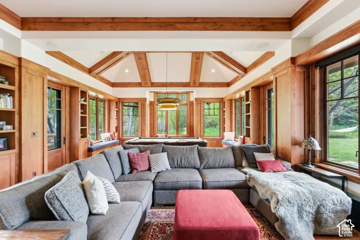 Vaulted wood-beamed ceilings, extensive wood paneling, built-in shelving, large windows, and a full-size billiards table