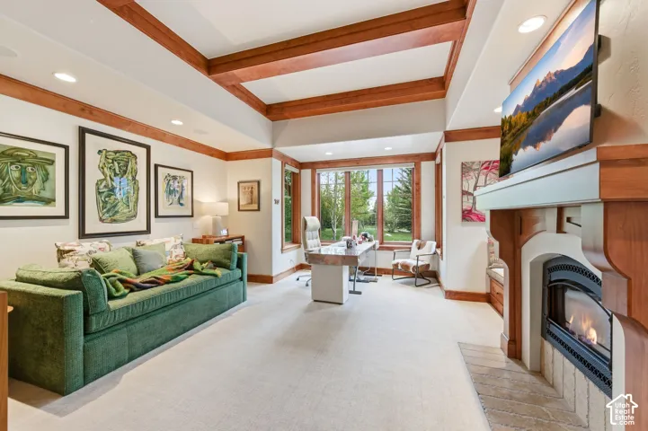 Coffered ceiling with wood beams, recessed lighting, expansive bay windows, wood-mantled fireplace, and built-in window seating