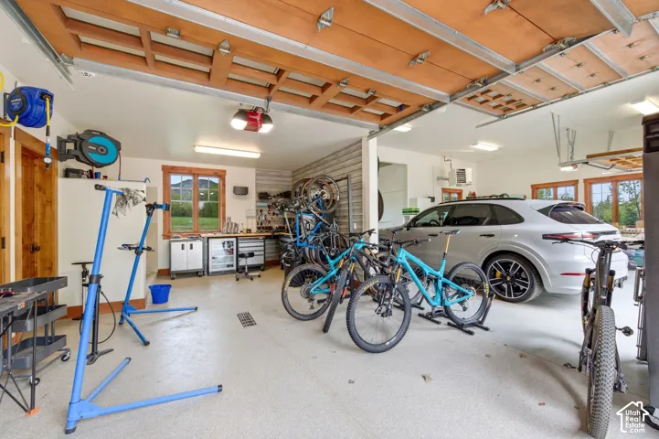 Spacious garage with wood-paneled garage door, multiple windows, built-in shelving, and light-toned flooring