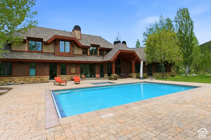 Stone and wood-sided exterior featuring a pitched roofline, dormer windows, and a covered patio