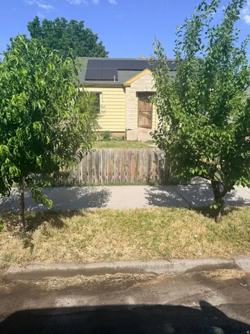 Yellow siding exterior with stone facade accents and a shingle roof featuring solar panels