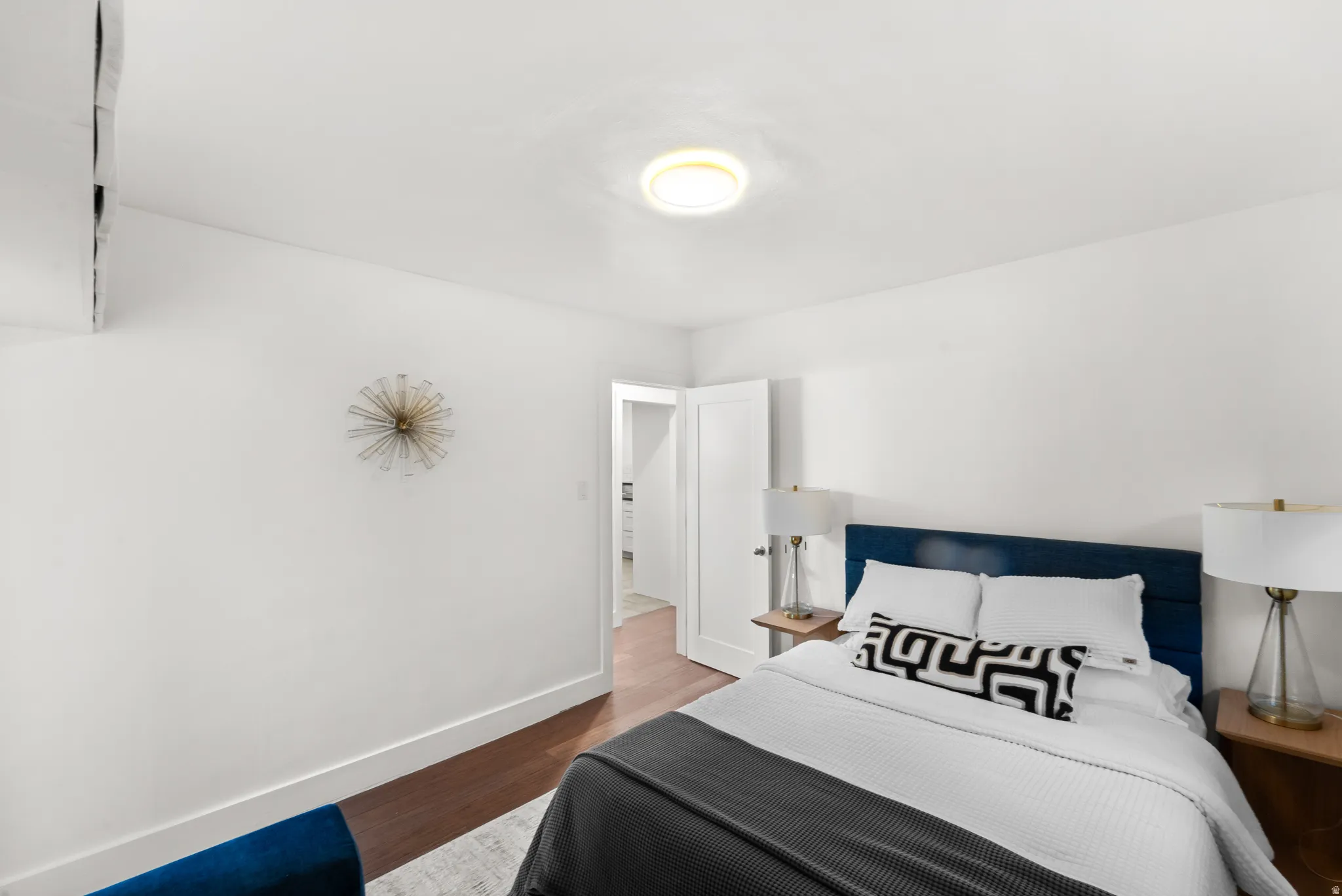 Bright primary bedroom featuring wood-finish flooring and white walls