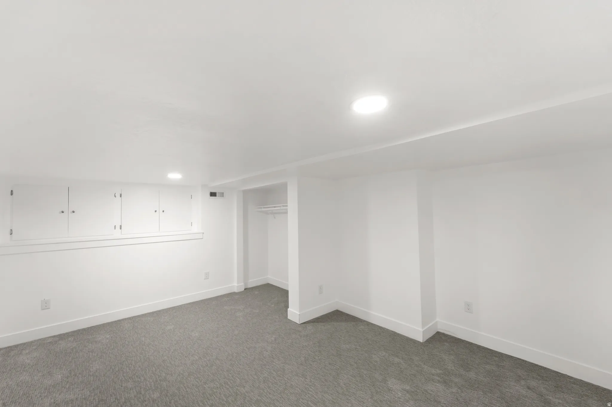 Carpeted interior space featuring white walls and recessed lighting