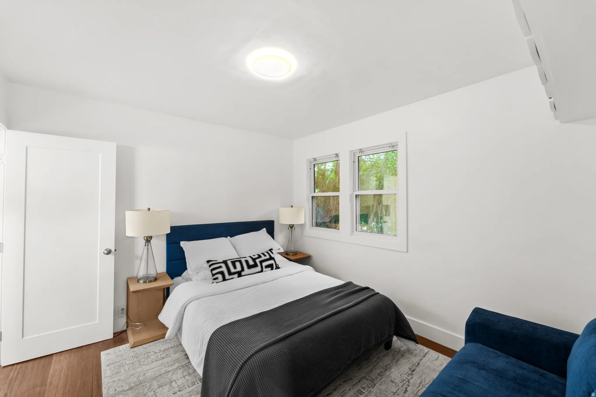 Bright primary bedroom featuring wood-finish flooring and white walls