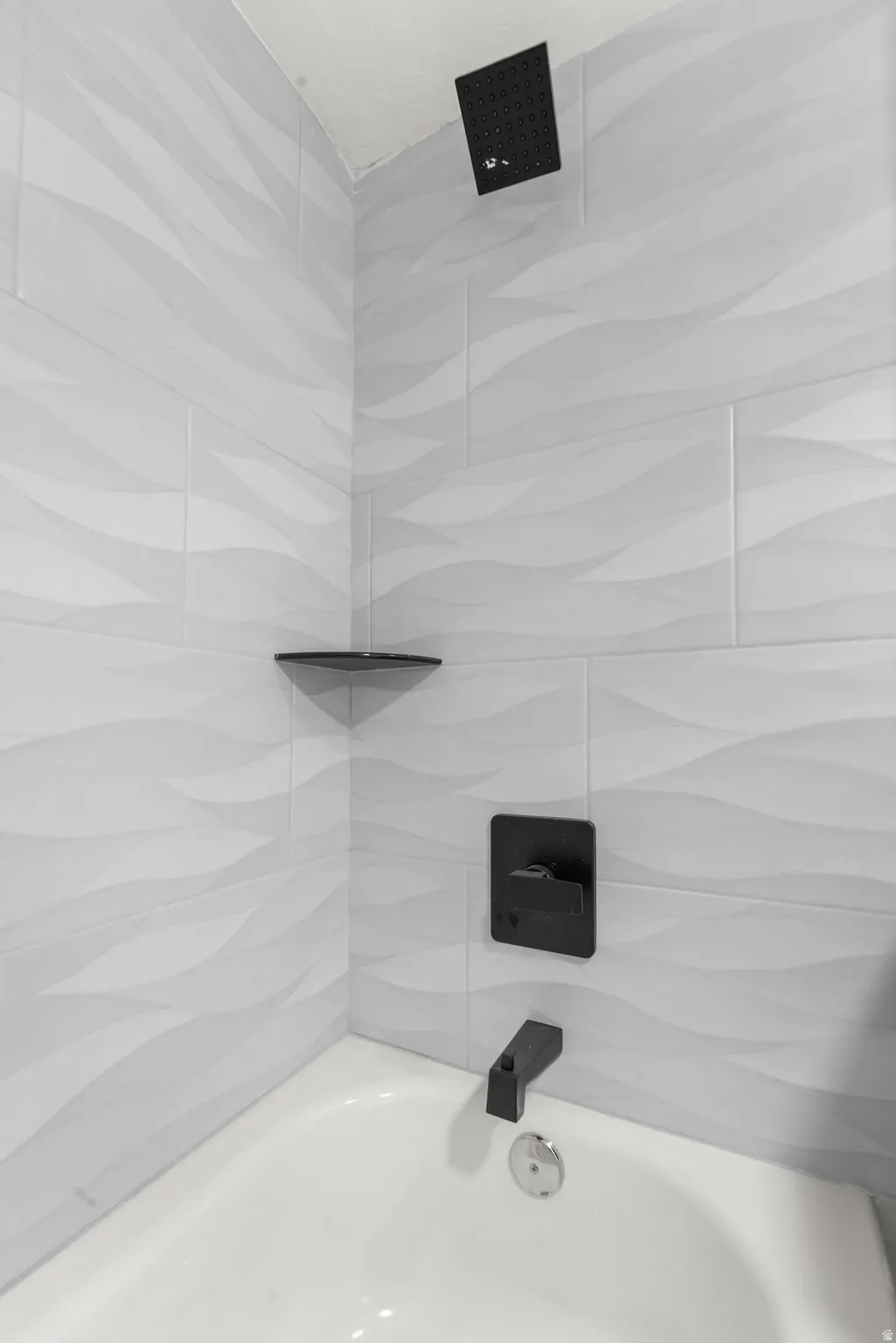 Bathtub with white walls and wave-patterned tile surround