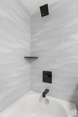 Bathtub with white walls and wave-patterned tile surround