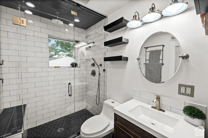 Contemporary bathroom featuring a spacious glass-enclosed shower with white subway tile walls and dark hexagonal floor tile