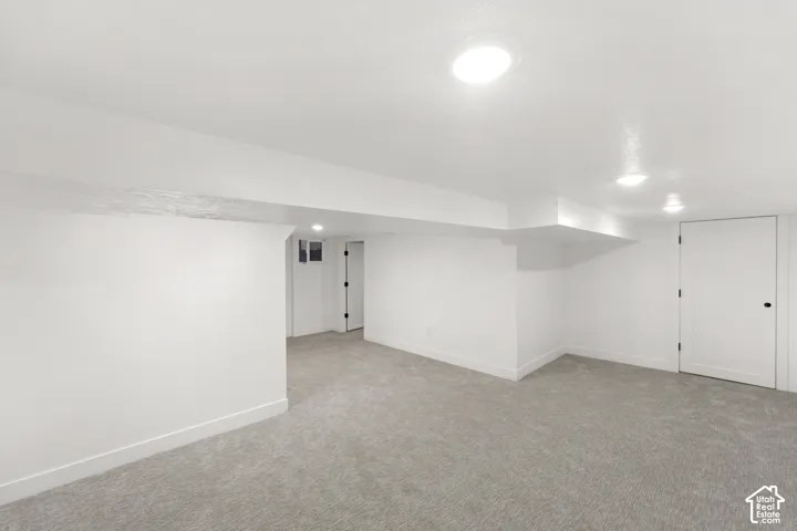 Spacious room featuring light gray carpeting, white painted walls, recessed lighting, and white baseboards