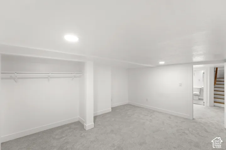 Spacious room with new gray carpeting, crisp white walls, and recessed lighting