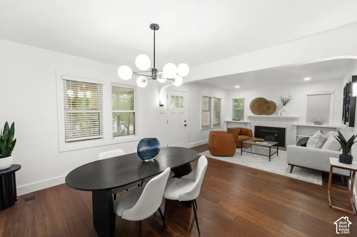 Spacious living area featuring wood-finish flooring, a modern chandelier, and a white-tiled fireplace with built-in shelving