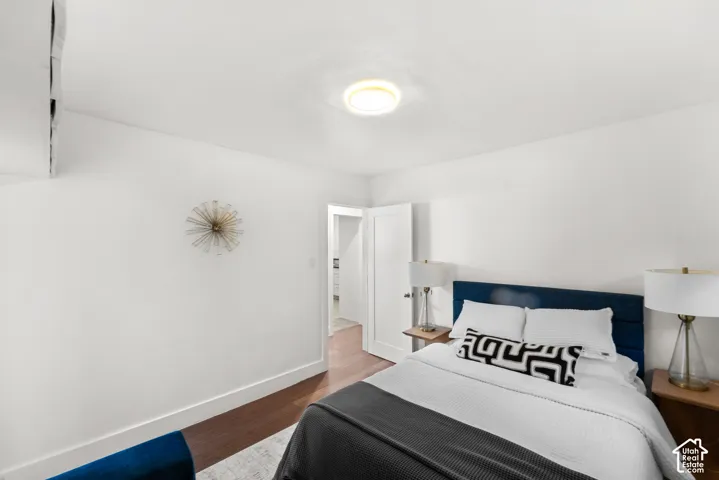 Bright primary bedroom featuring wood-finish flooring and white walls