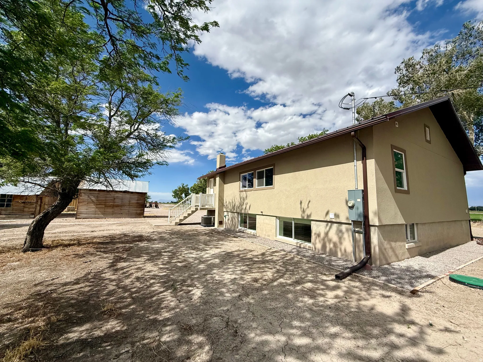 Two-story stucco residence with a white railing staircase and multiple ground-level windows