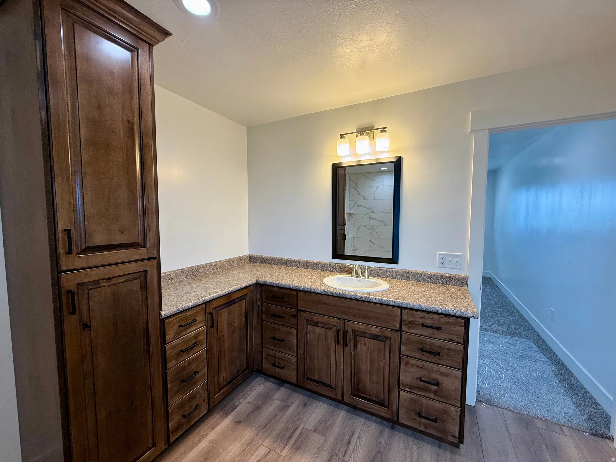 Spacious vanity featuring an integrated sink, granite-style countertop, and rich wood cabinetry with ample storage