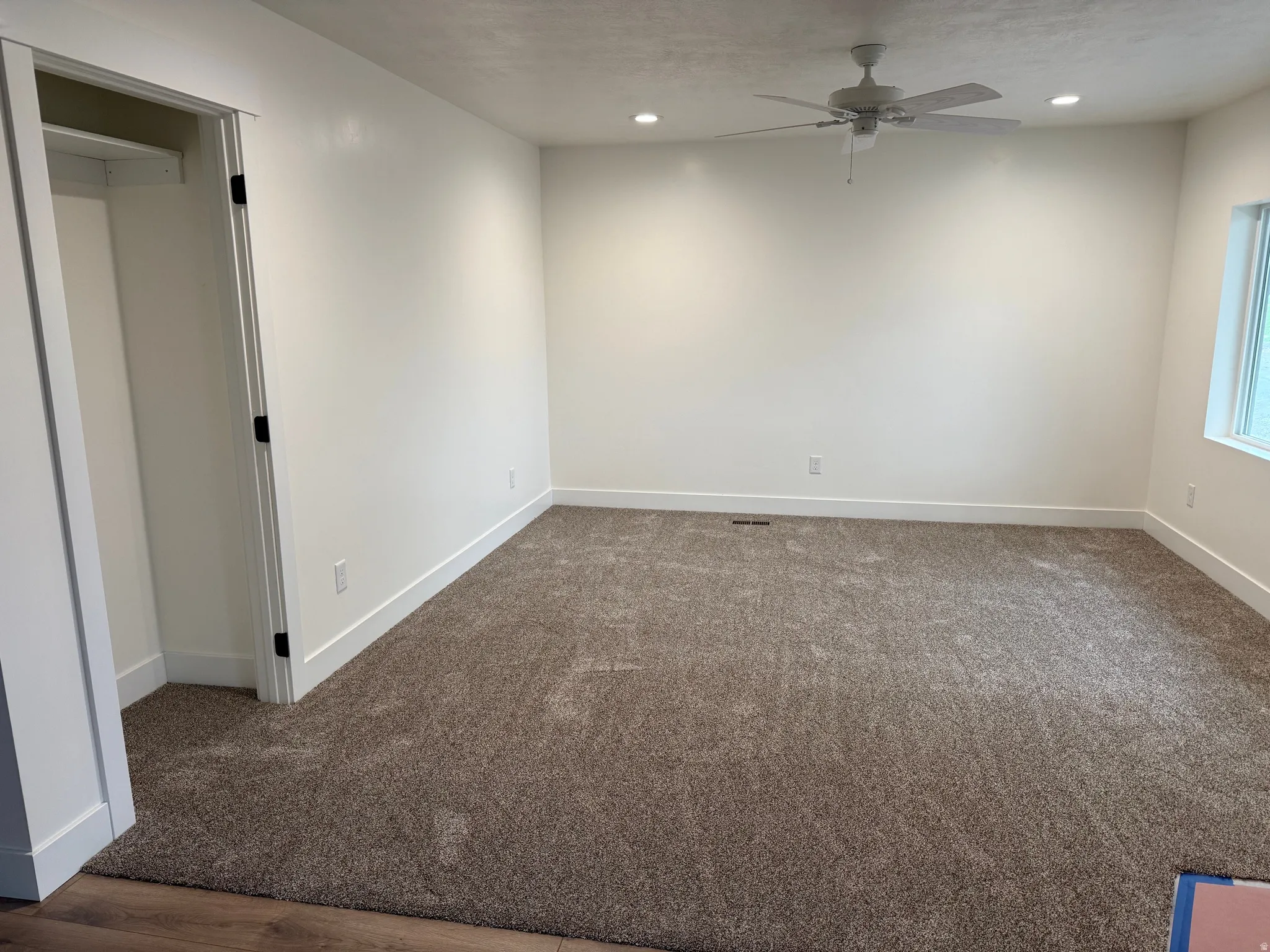 Carpeted room featuring a ceiling fan with integrated lighting, recessed lighting, and a window