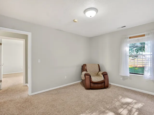 Carpeted room with light gray walls, white trim, and a window providing natural light