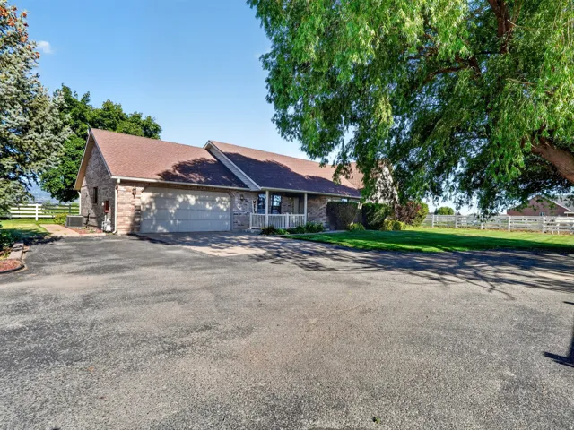 Brick exterior with a peaked roofline, attached two-car garage, and covered porch with white railings