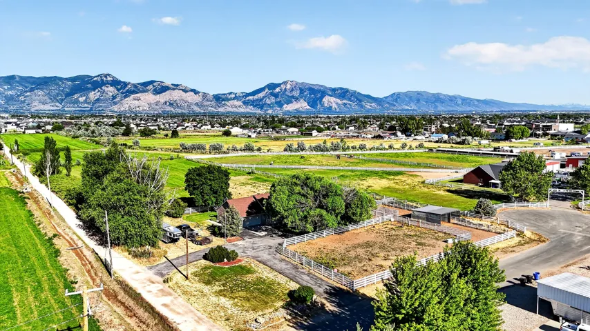 Expansive property with a residential structure, mature trees, and fenced enclosures