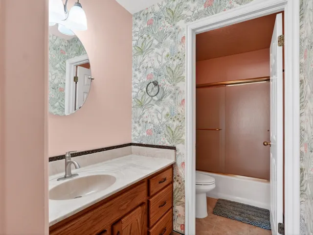 Bathroom vanity featuring wood cabinetry, a white countertop with an integrated sink, and an oval mirror