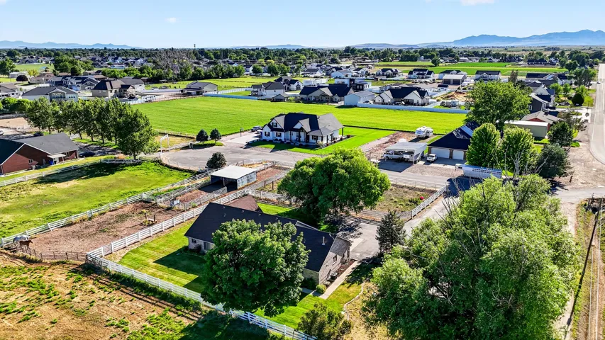 Expansive rural property featuring multiple outbuildings, fenced enclosures, mature trees, and a spacious green lawn