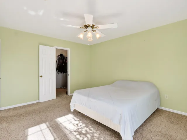 Carpeted bedroom featuring light green walls, a white ceiling, and a ceiling fan with integrated lighting