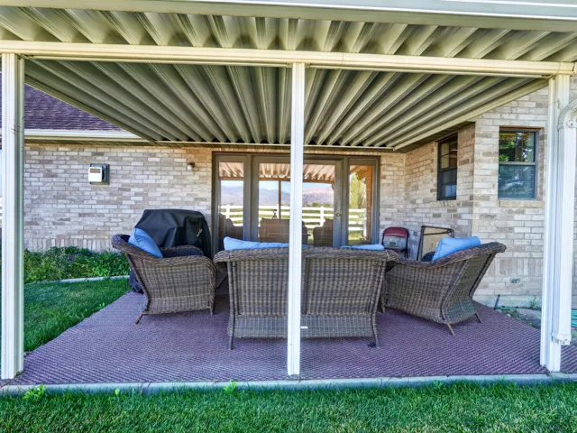 Covered outdoor patio featuring a textured floor surface, brick exterior, and multi-pane glass doors