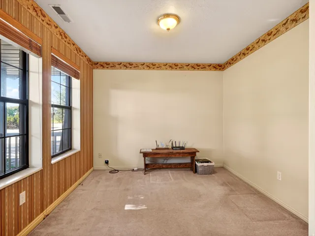 Room with two large windows, light brown carpet, and a decorative border at the ceiling line