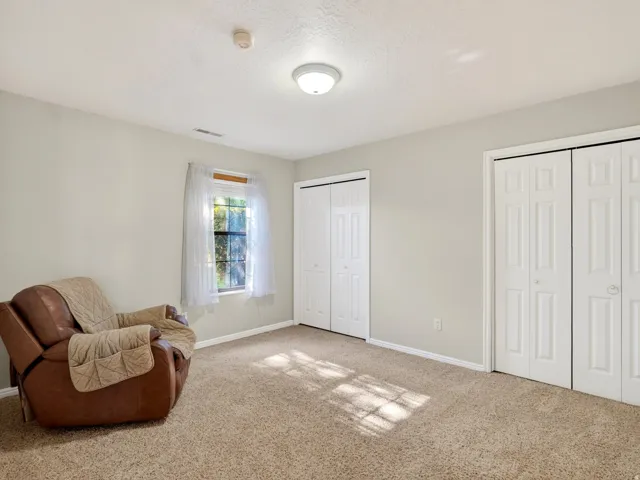 Carpeted room featuring a window with white trim, two sets of bi-fold closet doors, and light gray walls