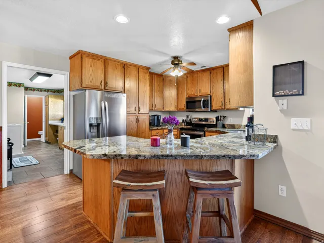 Kitchen featuring wood-finish flooring, wood cabinetry, granite-style countertops, and stainless steel appliances