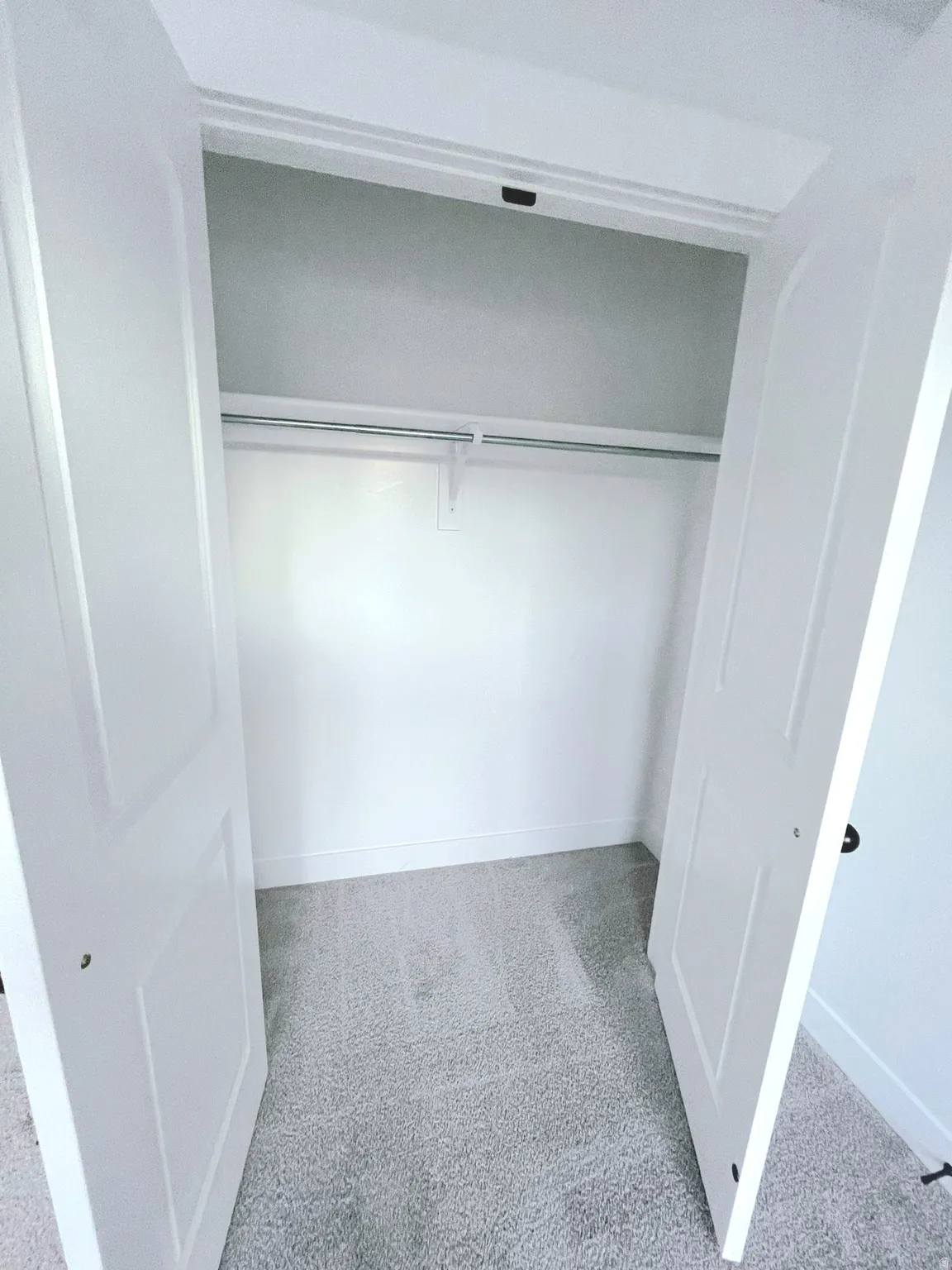 Full-size closet featuring bi-fold panel doors, upper shelf, and clothes hanging rod